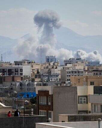 אנשים צופים מהגג בעשן עולה לאחר תקיפה בטהרן, איראן | AP אנשים צופים מהגג בעשן עולה לאחר תקיפה בטהרן, איראן | AP