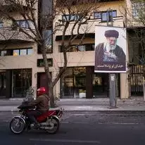אופנוע חולף על פני תמונה של המנהיג העליון האיראני, האייתוללה עלי חמינאי, לאורך רחוב ריק בטהרן, איראן | AP/Vahid Salemi אופנוע חולף על פני תמונה של המנהיג העליון האיראני, האייתוללה עלי חמינאי, לאורך רחוב ריק בטהרן, איראן | AP/Vahid Salemi