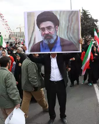 גבר איראני מחזיק תמונה של מוג'תבא חמינאי, בנו של המנהיג העליון של איראן, כשהוא משתתף בחגיגות 47 שנה למהפכה האסלאמית בטהרן | EPA גבר איראני מחזיק תמונה של מוג'תבא חמינאי, בנו של המנהיג העליון של איראן, כשהוא משתתף בחגיגות 47 שנה למהפכה האסלאמית בטהרן | EPA